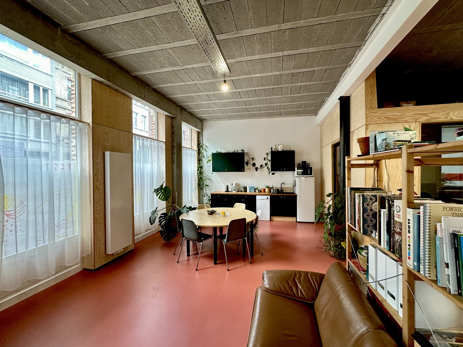 The round table by the windows, with the kitchen and shelving behind.